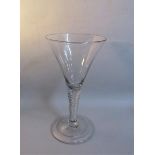 A 19c English toasting glass with a trumpet bowl on an opaque twist tapering stem, with domed folded