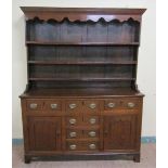 An early 18c English oak three drawer dresser with a panel back rack having three open shelves under