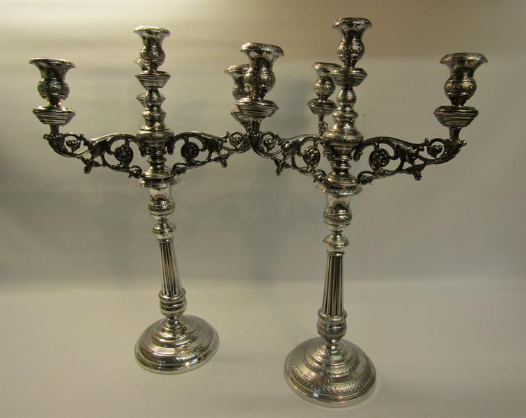 A pair of 19c silver three branch candelabra's with knot fluted tapering columns and raised on