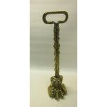 A 19c brass and iron lion paw door stop with a leaf form carrying handle. 39cms h.