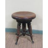 A Victorian oak revolving piano stool supported on four ring turned legs with claw and glass ball