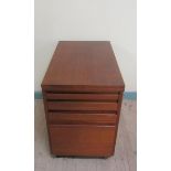 A 1970's teak office cabinet with hinged fold over revolving table top and having three long pull-