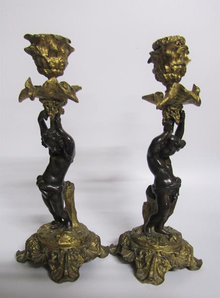 A pair of late 19c gilt and patinated bronze candlesticks with putti columns supporting the socles