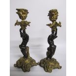 A pair of late 19c gilt and patinated bronze candlesticks with putti columns supporting the socles