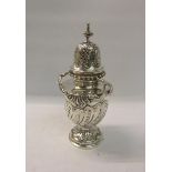 A late Victorian large silver sugar caster of decorative form. Three quarter lobed and embossed with