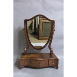 A late Georgian mahogany shield shaped toilet glass on a serpentine base fitted three short