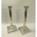 A pair of Edwardian silver column candlesticks on square stepped gadrooned bases, with fluted