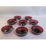 A set of eight aubergine coloured glass single handled coupes with white enamelled rims, 10.5cms