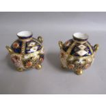 A pair of Davenport globular two handled vases supported on three gilt ball feet and decorated