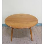 An Ercol teak circular low table on four splayed baluster legs. 75cms d x 46cms h.