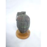 An inert Second War British Mills Grenade dated 1942 on wooden base