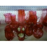 A selection of cranberry tinted glassware including tapered jugs, vases, circular bowl,