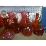 A selection of cranberry tinted glassware including four tapered wine jugs, carafe, spill vase,