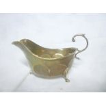 A George V silver sauce boat with scroll handle on three hoof feet, Birmingham marks,