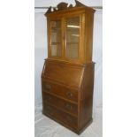 An Edwardian oak bureau bookcase with pigeon holes enclosed by a fall front above three long