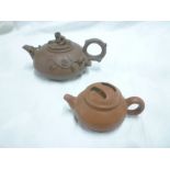 A Chinese terracotta circular squat-shaped teapot decorated in relief with grapes and leaves and