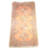 An Eastern hand-knotted wool rug with geometric decoration on orange ground,