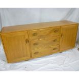 A 1960's Ercol light elm sideboard with three central drawers flanked by cupboards enclosed by two