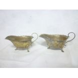 A pair of George V silver classical-shaped sauce boats with scroll handles on hoof feet,