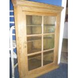 A 19th Century polished pine hanging corner cupboard with shelves enclosed by a central glazed door