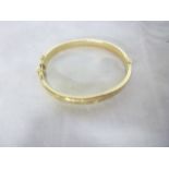 A 9ct gold oval bangle with engraved decoration