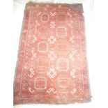 An Eastern hand-knotted wool rug with geometric decoration on red ground,
