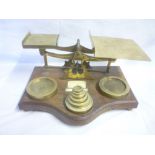 An old brass balance scales mounted on oak serpentine fronted stand inset with brass stacking