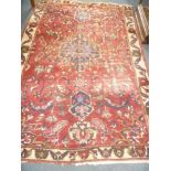 A large Eastern hand-knotted wool rug with floral decoration on red and cream ground 9' 6" x 6' 6"