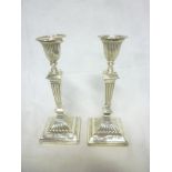 A pair of late Victorian silver candlesticks with square tapered stems and square bases,