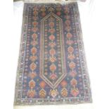 An Eastern style wool rug with geometric decoration on blue ground 70" x 42"