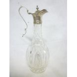 A mid 19th Century cut glass and silver mounted oil/vinegar jug with hinged lid and scroll handle,
