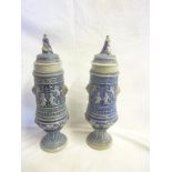 A pair of German pottery pedestal vases and covers decorated in relief with classical figures and