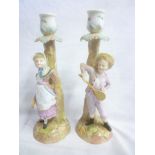 A pair of German porcelain candlesticks, the rustic stems modelled with boy and girl tennis players,