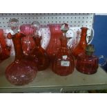 Three cranberry tinted glass wine jugs with loop handles,