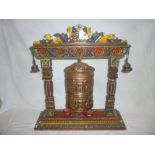 A Tibetan brass prayer wheel on painted carved wood stand