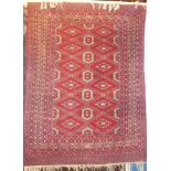 An Eastern wool rug with medallion decoration on red ground,