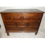 An 18th Century oak rectangular coffer with multiple panelled front and pegged hinged lid on block