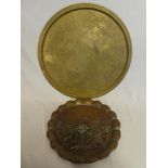 An unusual copper circular plaque decorated in relief with houses within a landscape,