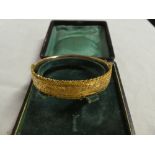 A 9ct gold oval bangle with engraved decoration,