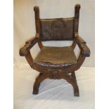 A 19th Century Continental carved walnut X-frame easy chair with raised mask head and embossed