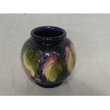 A Moorcroft pottery circular vase with fruit and leaf decoration on blue ground,