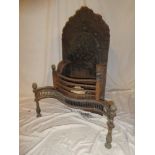 An old brass mounted iron serpentine fronted fire grate with cast iron arched back decorated in