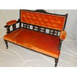 A late Victorian carved mahogany two seat settee upholstered in buttoned fabric on turned legs with