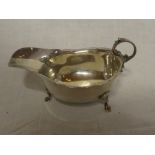 A George V silver classical-shaped sauce boat with scroll handle on three hoof feet,