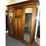 A Victorian figured walnut triple wardrobe with internal drawers and sliding trays enclosed by two