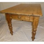 An old polished pine rectangular kitchen table with a drawer in one end on turned tapered legs,