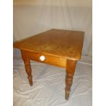 An old polished pine rectangular kitchen table with a single drawer in one end on turned tapered