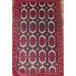 An Eastern style wool rug with geometric decoration on red ground,