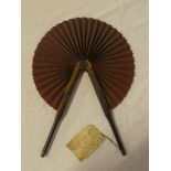An early leather mounted fabric circular opening fan with old label "This fan was found in 1912 on