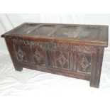 An 18th Century oak rectangular coffer with four carved panels to the front and hinged lid on block